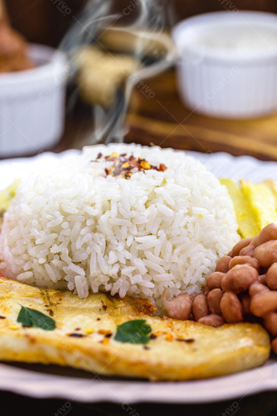 Prato brasileiro com arroz branco fumegante feijão marrom e peixe grelhado fresco