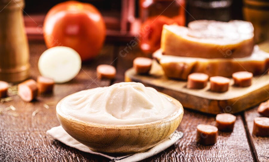 Molho cremoso branco em tigela de madeira com salsicha queijo tomate e cebola