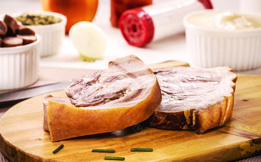 Fatias de carne de porco assada na tábua de madeira rústica com temperos