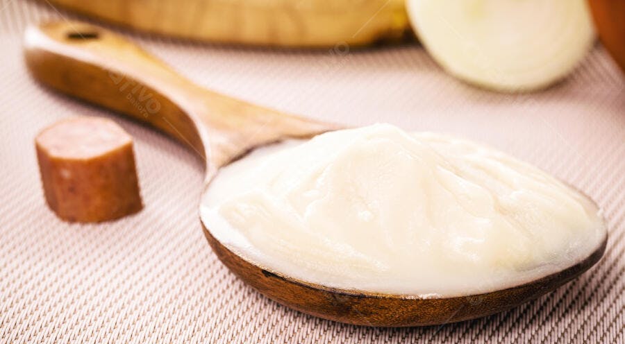 Colher de pau com creme de coco caseiro e rapadura na mesa rústica