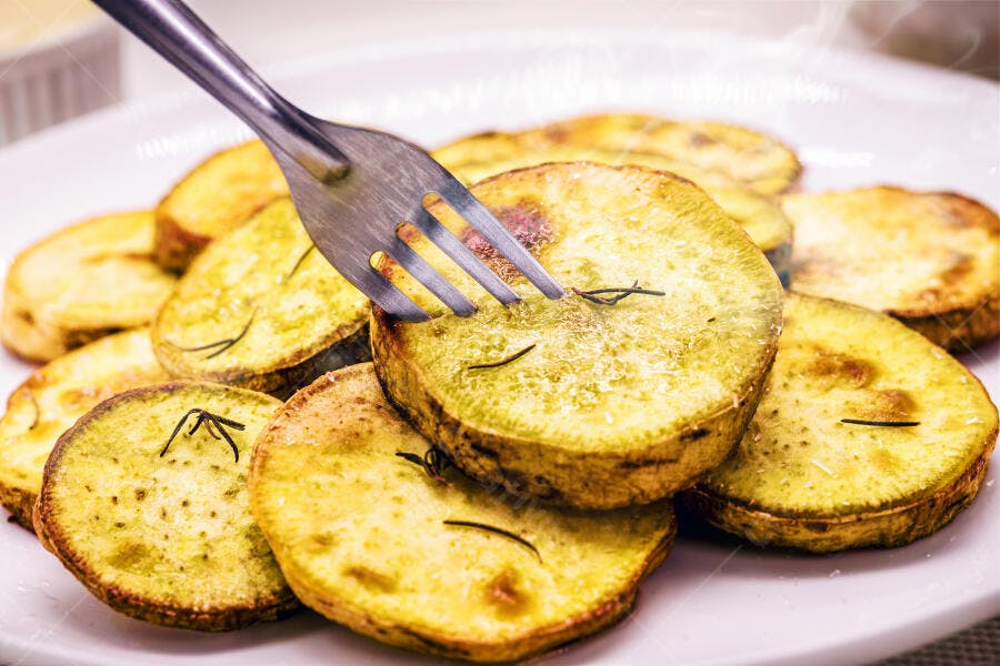 Fatias de batata doce assada com alecrim no prato e garfo