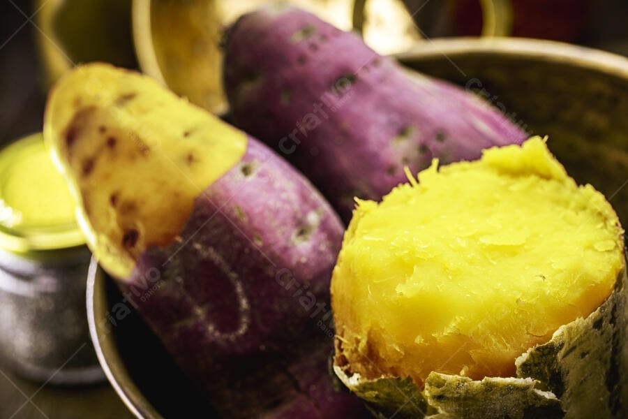 Batata doce roxa e amarela cozida descascada em tigela de madeira