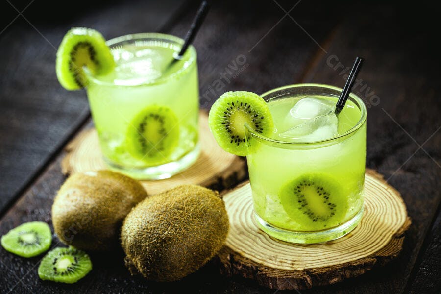 Coquetéis verdes de kiwi com gelo e fatias em tábua de madeira escura