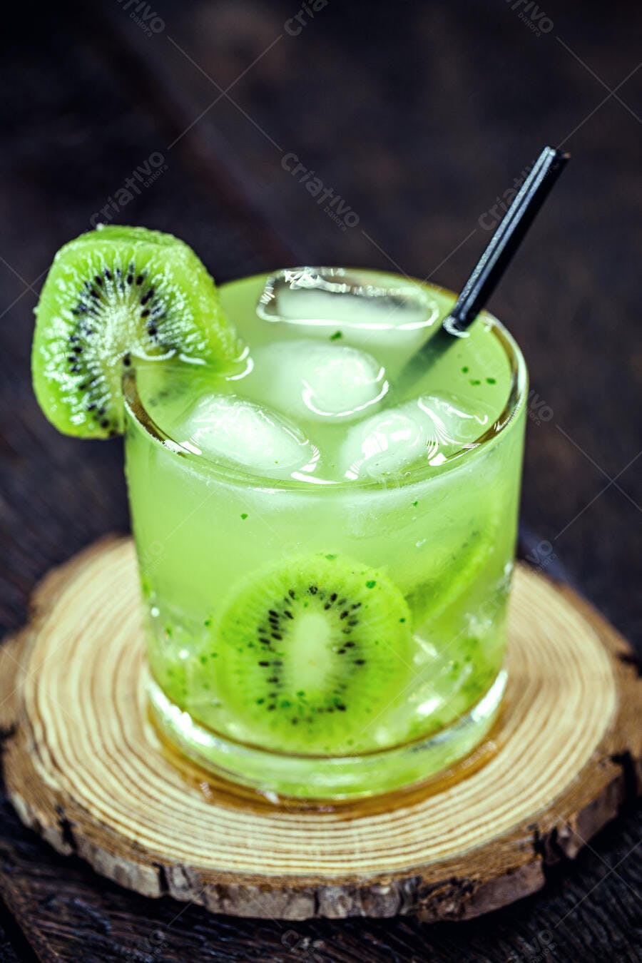Coquetel refrescante de kiwi com gelo e fatias de fruta em fundo de madeira escura