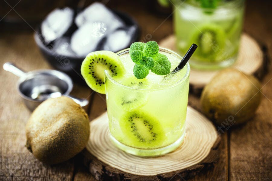 Caipirinha de kiwi verde e hortelã em copo sobre madeira rústica com gelo