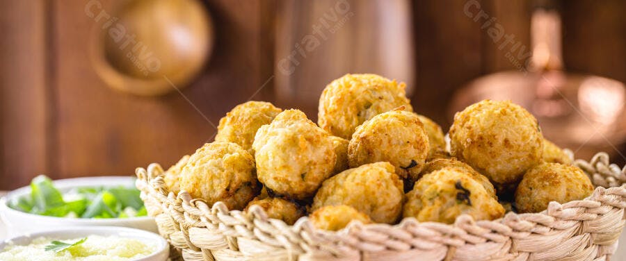 Bolinhos de bacalhau crocantes em cesta de palha com molho verde