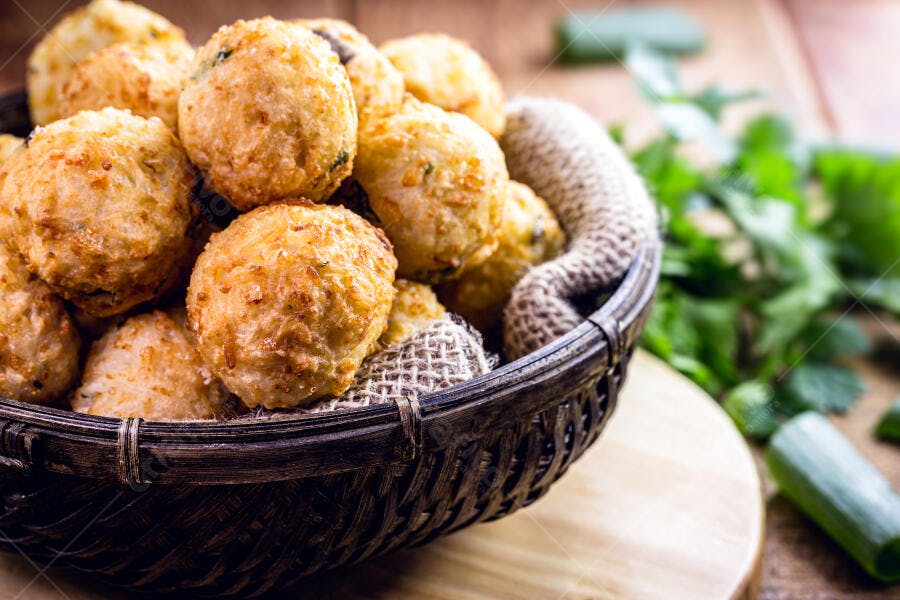 Bolinhos fritos dourados em cesta rústica com temperos frescos