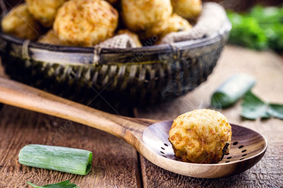 Salgado frito dourado com cebolinha em colher de pau rústica
