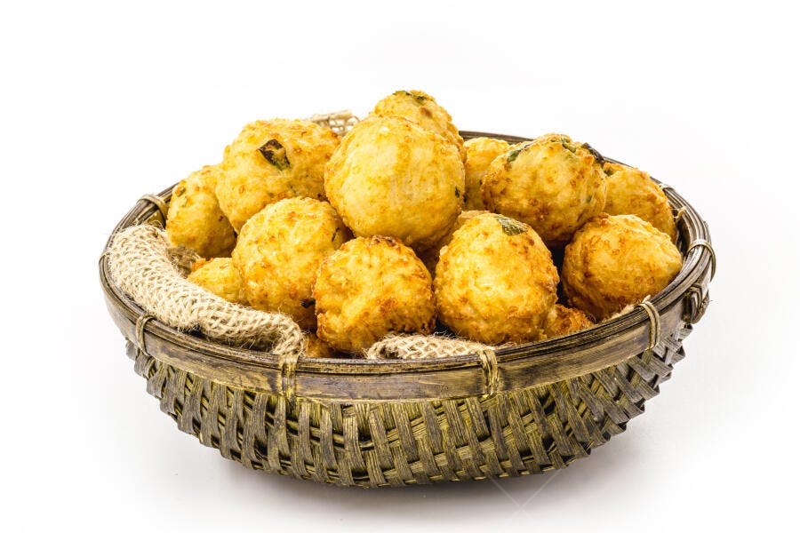 Bolinhos de arroz fritos dourados em cesta de vime fundo branco