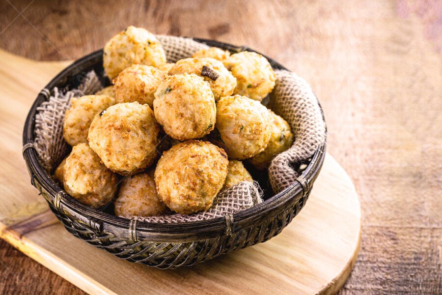 Bolinhos de arroz fritos crocantes dourados em cesta rústica de madeira