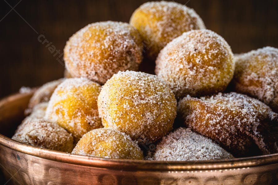 Brigadeiros de festa amarelos com açúcar em tigela de cobre