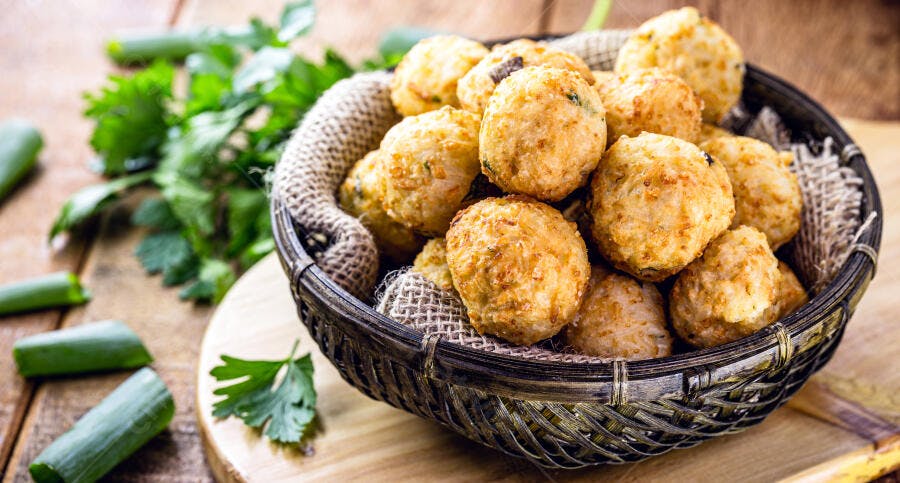 Bolinhos de arroz fritos crocantes em cesta rústica com temperos verdes