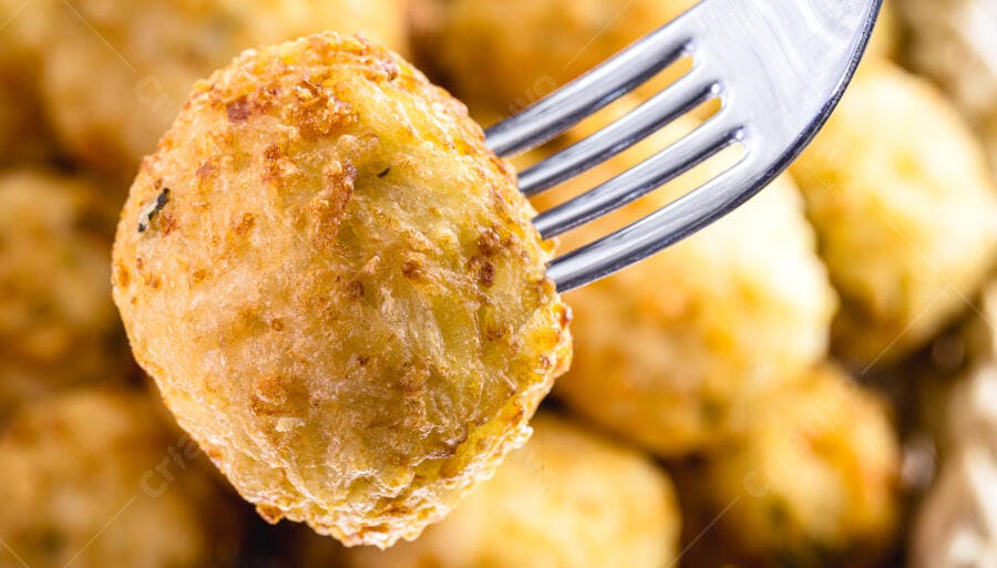 Bolinho frito dourado crocante em close-up sendo pego por garfo