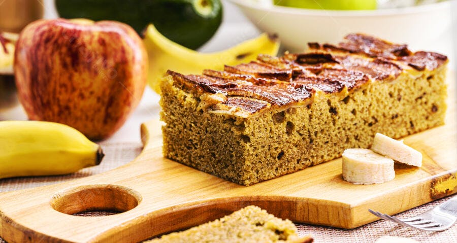 Fatia de bolo de maçã e banana caseiro com frutas frescas em tábua de madeira