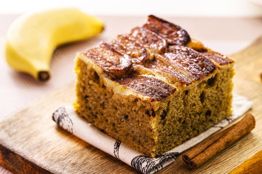 Bolo de banana com fatias caramelizadas em tábua de madeira com canela e fruta amarela