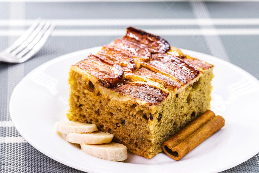Bolo de banana fresco com fatias caramelizadas e canela em mesa xadrez