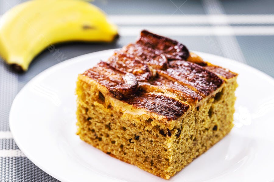 Fatia de bolo de banana caseiro com cobertura caramelizada em prato branco