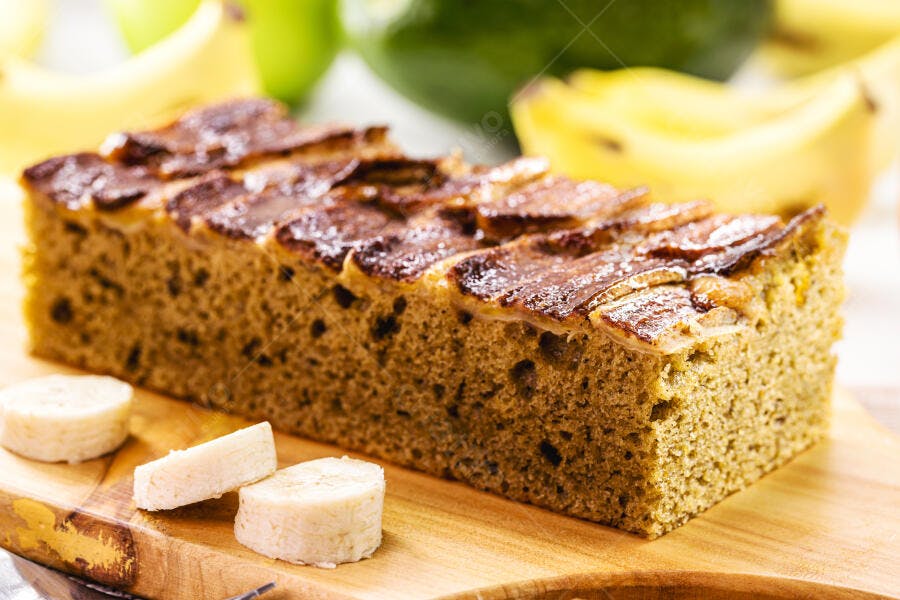 Fatia de bolo de banana caseiro com cobertura caramelizada em tábua de madeira