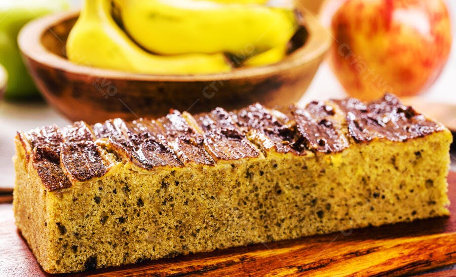 Bolo de banana caseiro com fatias caramelizadas e frutas frescas na cozinha