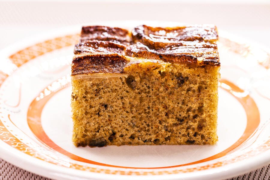 Bolo de banana castanho com cobertura caramelizada em prato decorado