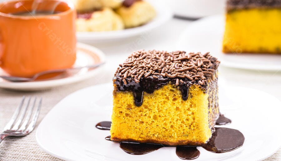 Fatia de bolo de cenoura com cobertura de chocolate e granulado em prato branco