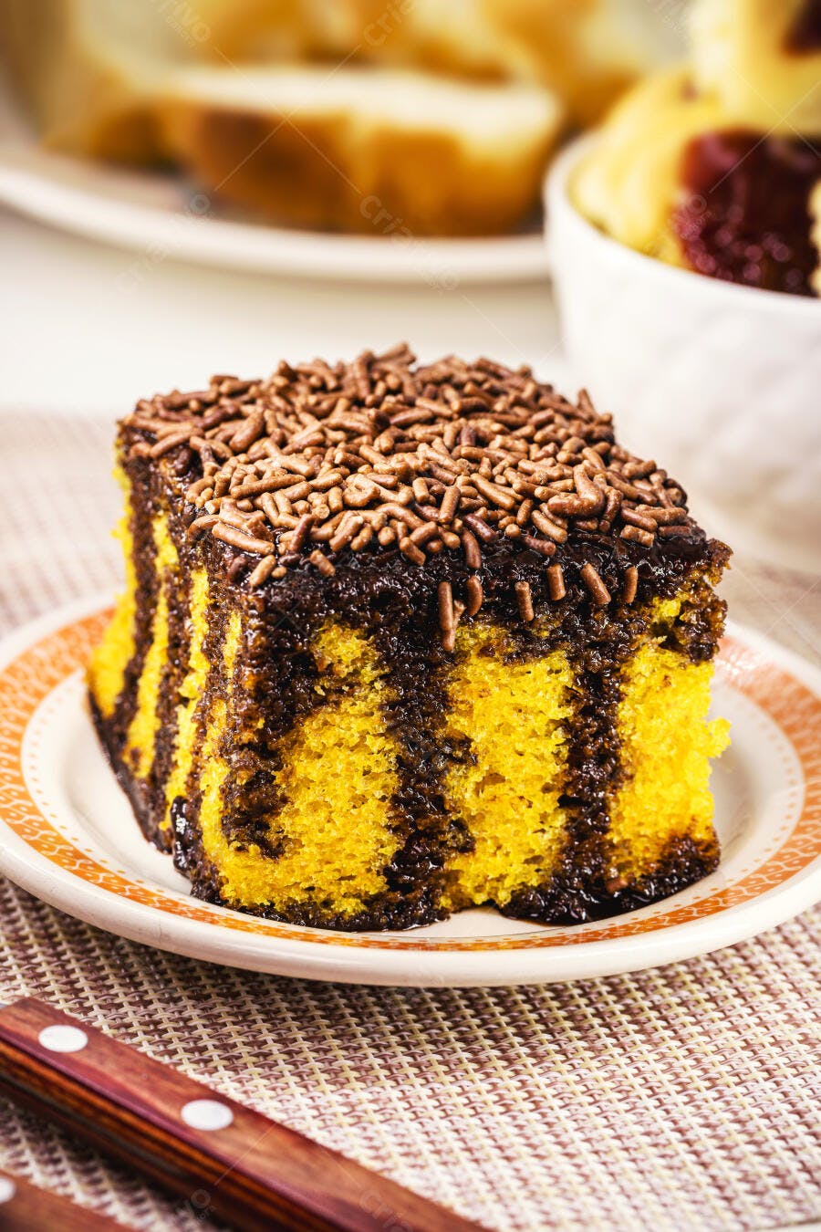 Fatia de bolo de cenoura com cobertura de chocolate e granulado em prato