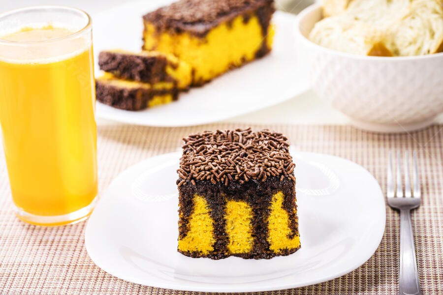 Bolo zebrado amarelo e marrom com granulado e suco de laranja no café da manhã