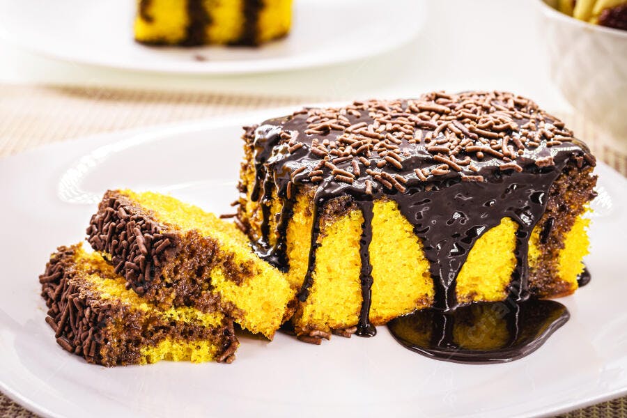 Bolo de cenoura com cobertura de chocolate e granulado em prato branco