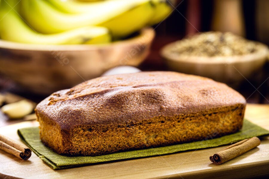 Bolo de banana caseiro recém-assado com canela em bancada de madeira rústica e bananas