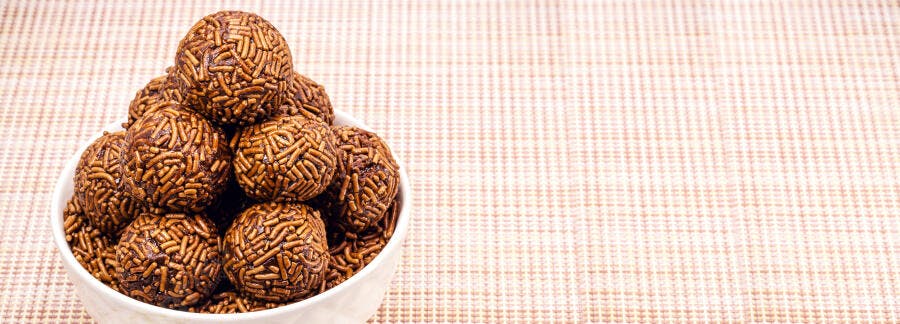 Brigadeiros brasileiros de chocolate com granulado em tigela branca sobre fundo claro