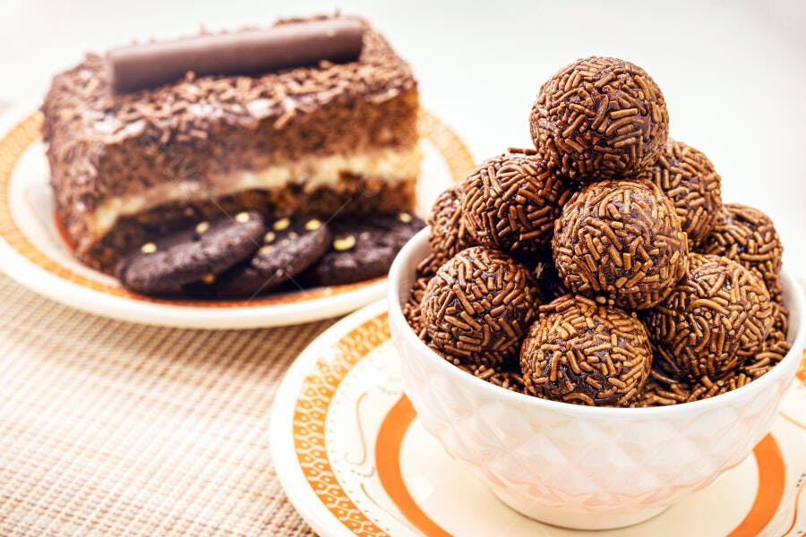 Brigadeiros de chocolate escuro e bolo granulado festivos em mesa clara