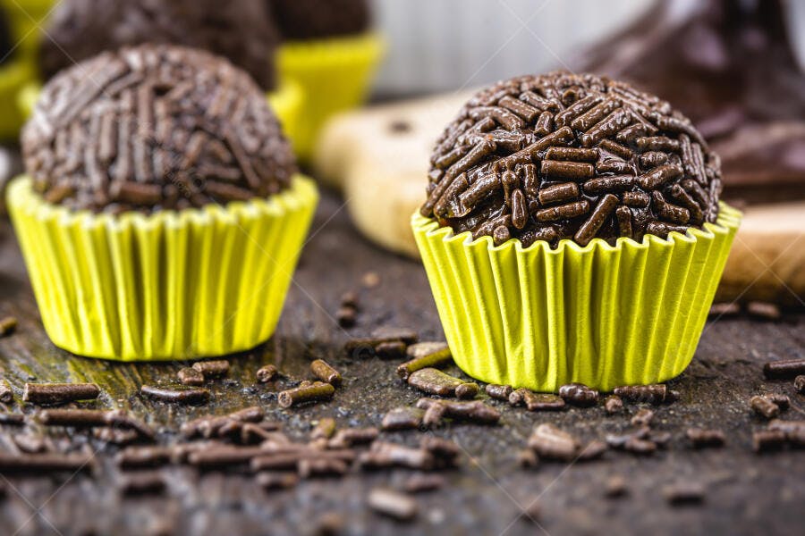 Brigadeiro brasileiro em forminha amarela com granulado de chocolate em mesa rústica