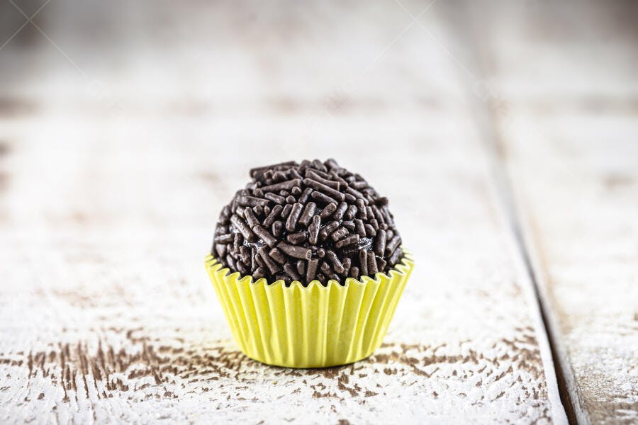 Brigadeiro brasileiro de chocolate com granulado em forminha amarela sobre madeira