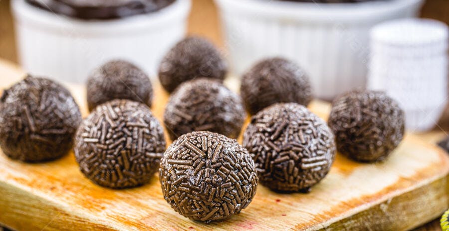 Brigadeiros de chocolate escuro com granulado em tábua de madeira