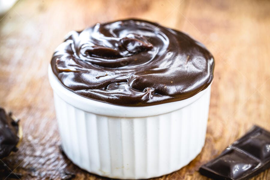 Creme de chocolate escuro brilhante em ramekin branco sobre madeira para sobremesa festiva