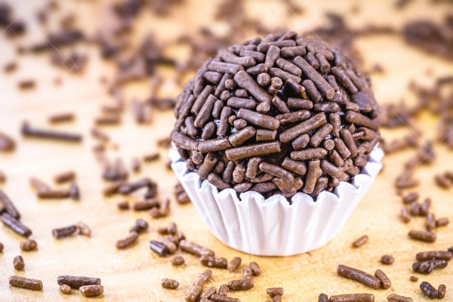 Brigadeiro brasileiro de chocolate granulado em forminha branca sobre madeira