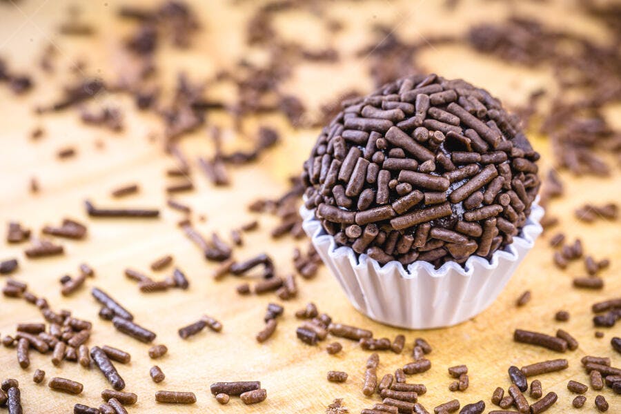 Brigadeiro brasileiro com granulado em forminha branca sobre madeira clara
