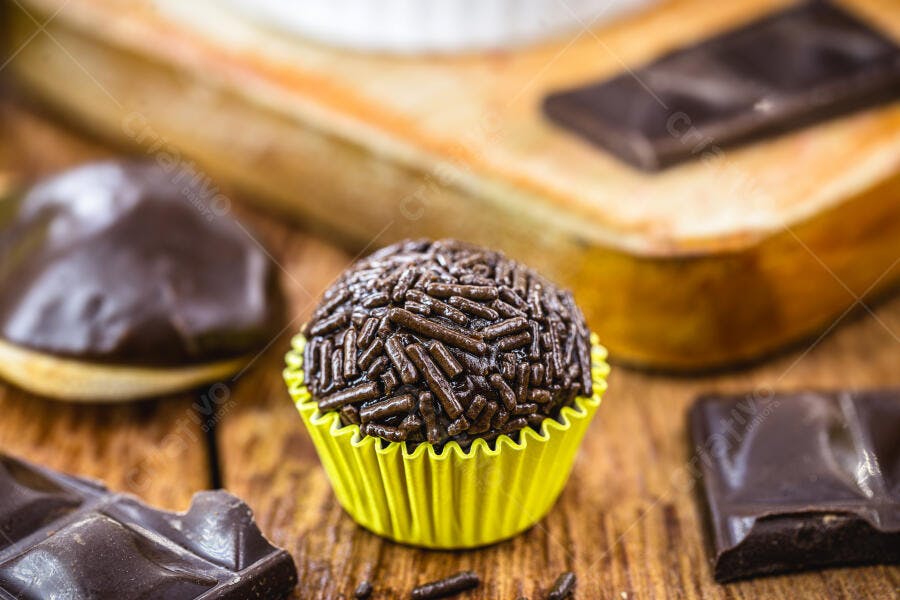 Brigadeiro de chocolate com granulado em forminha amarela sobre madeira