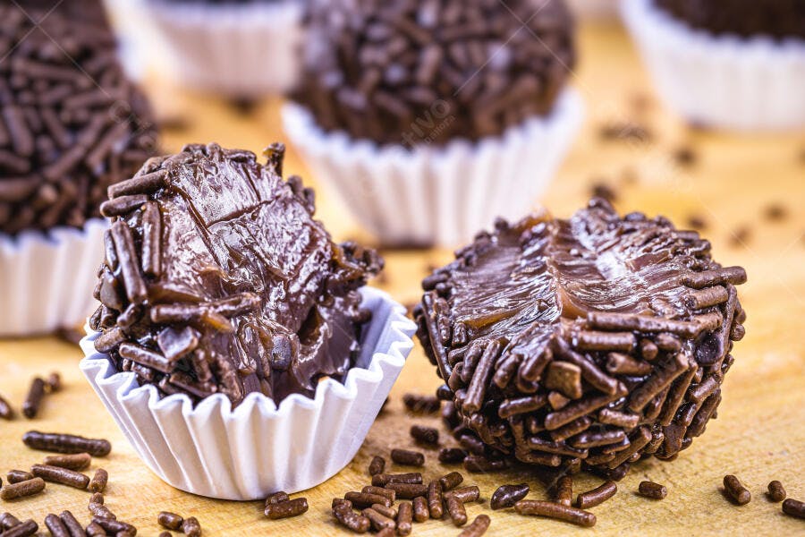 Brigadeiros de chocolate em forminhas brancas sobre madeira clara