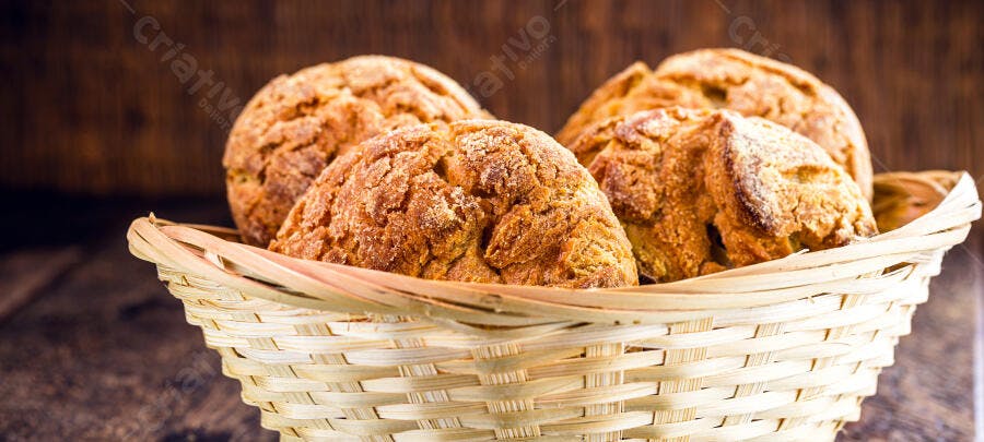 Pãezinhos rústicos de milho em cesta de vime sobre mesa de madeira