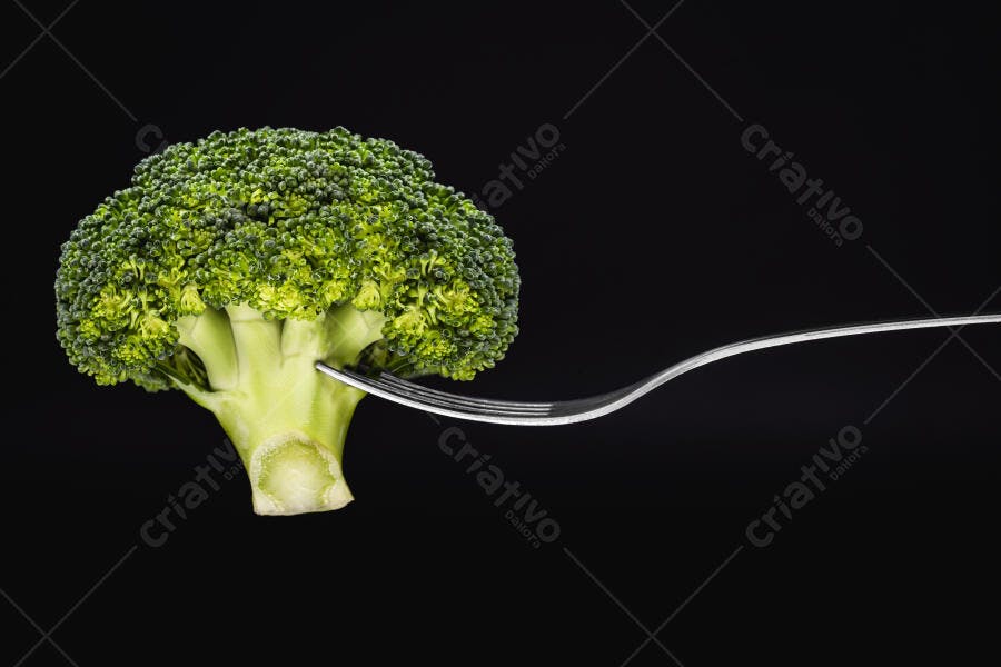 Brócolis verde fresco com garfo em fundo preto para alimentação saudável