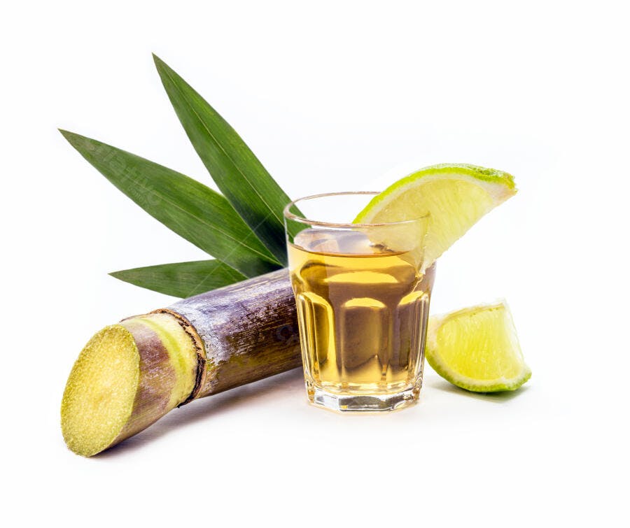 Cachaça em copo com limão e cana de açúcar em fundo branco