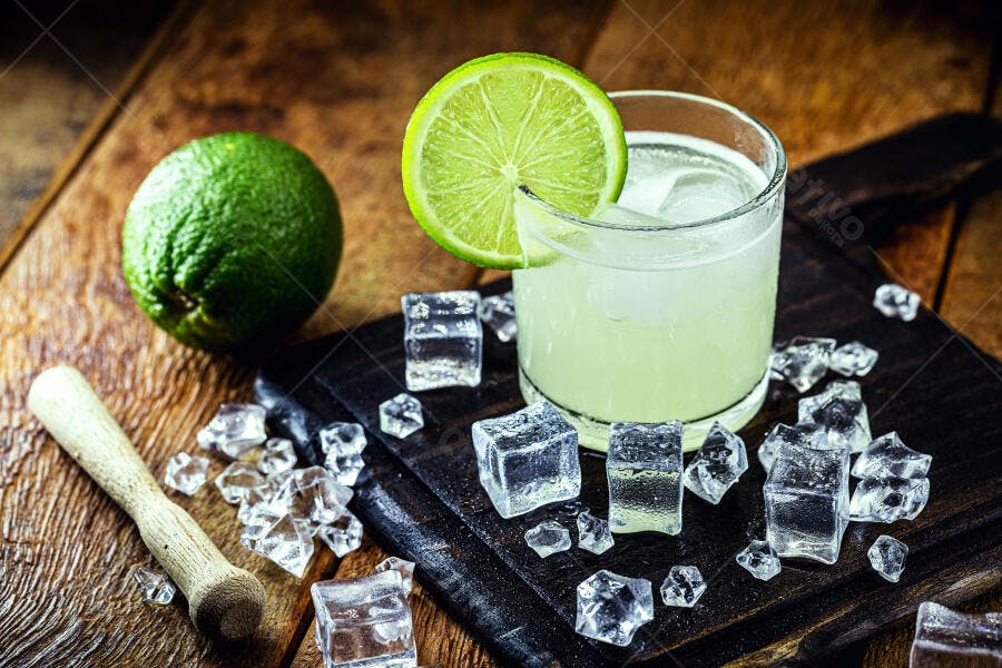 Coquetel de limão refrescante com gelo e lima em tábua de madeira rústica