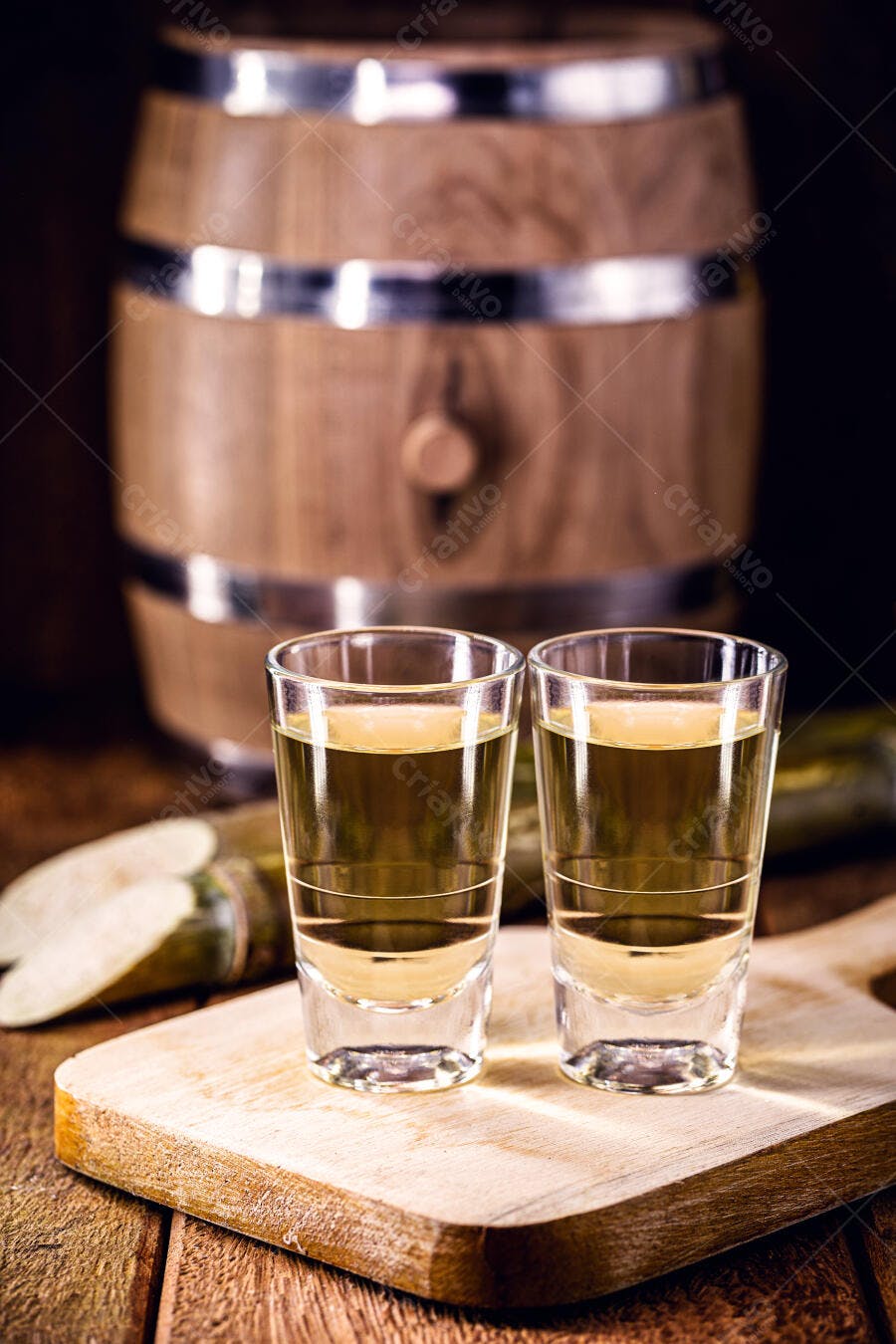 Dois copos de cachaça em tábua de madeira com cana e barril rústico