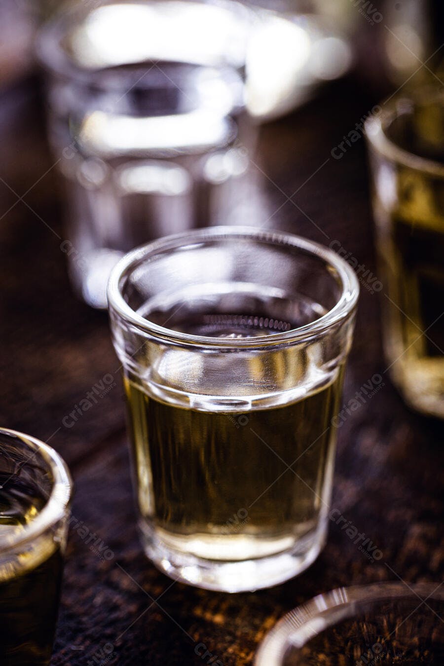 Shot de cachaça ou tequila em copo de vidro sobre mesa de madeira rústica