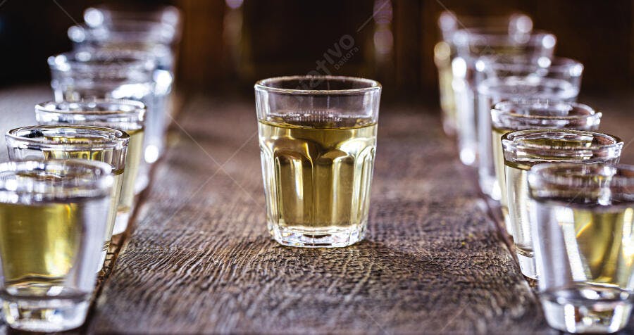 Copos de shot com bebida dourada em mesa de madeira rústica escura