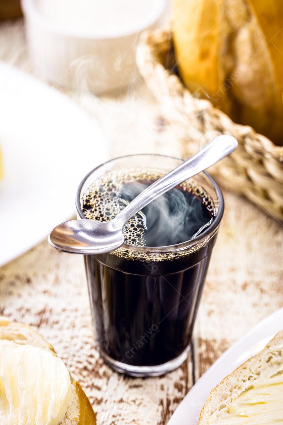 Café quente fumegante em copo de vidro com pão e manteiga no café da manhã