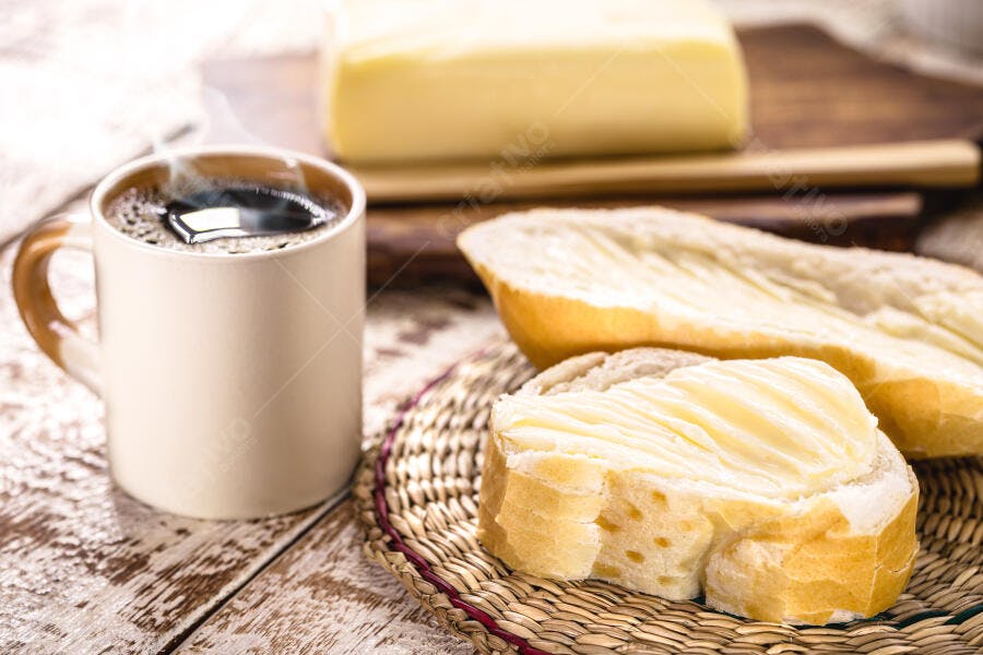 Pão francês com manteiga café quente em mesa rústica de madeira