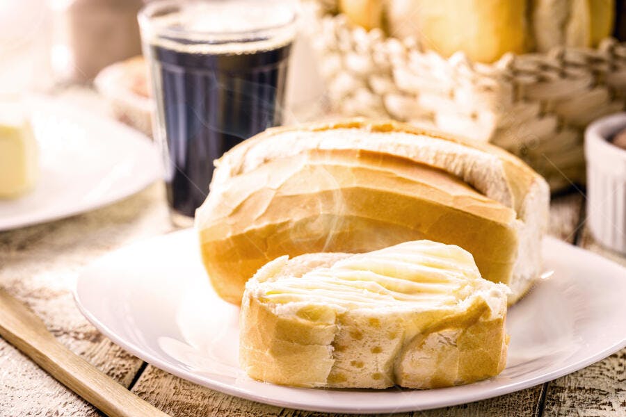Pão francês com manteiga fresca na mesa rústica para café da manhã