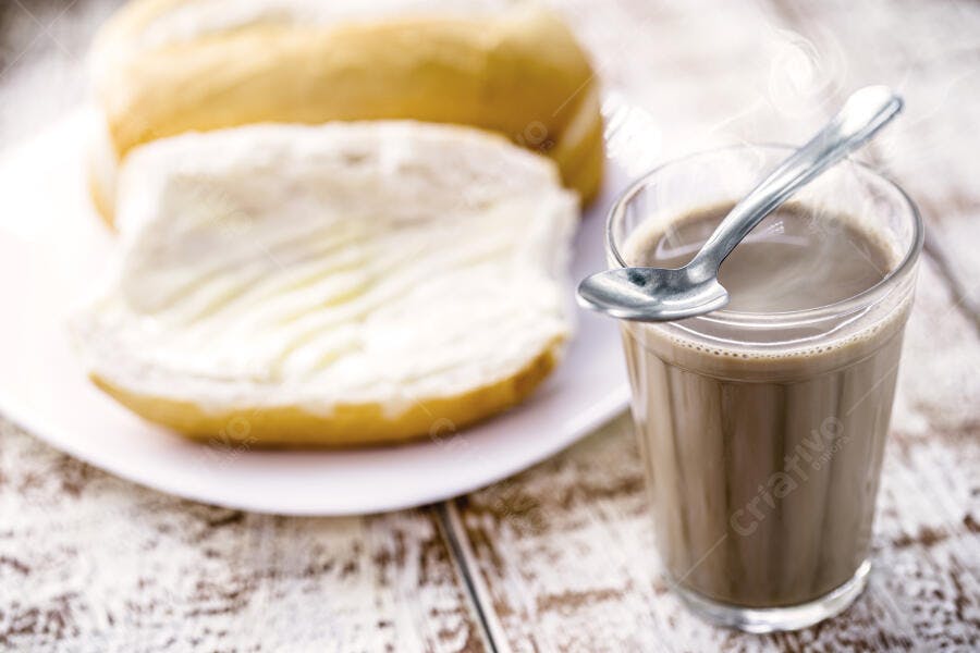 Pão francês com manteiga e café com leite quente no café da manhã